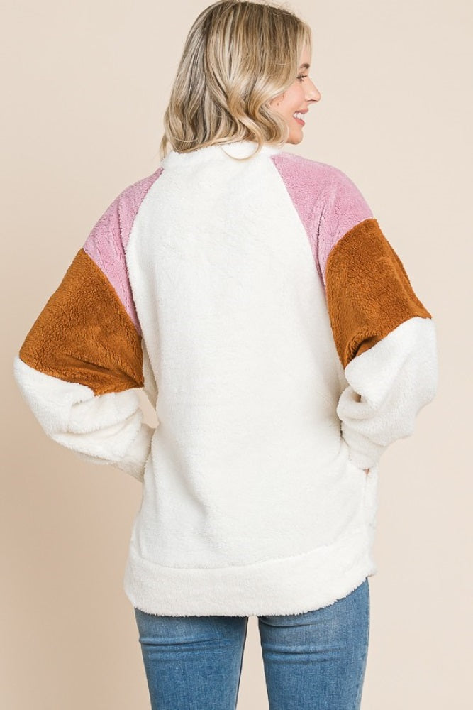 woman wearing a cozy color block fleece pullover with pink, brown, and white sleeves, shown from the back