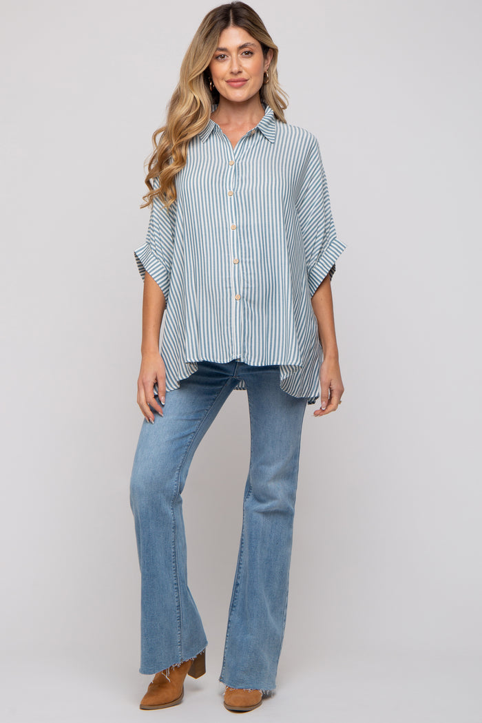 woman wearing a light blue striped button-up maternity shirt and flared jeans, displaying her baby bump