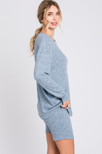 woman wearing a light blue ribbed sweater and matching shorts, posing sideways against a plain background