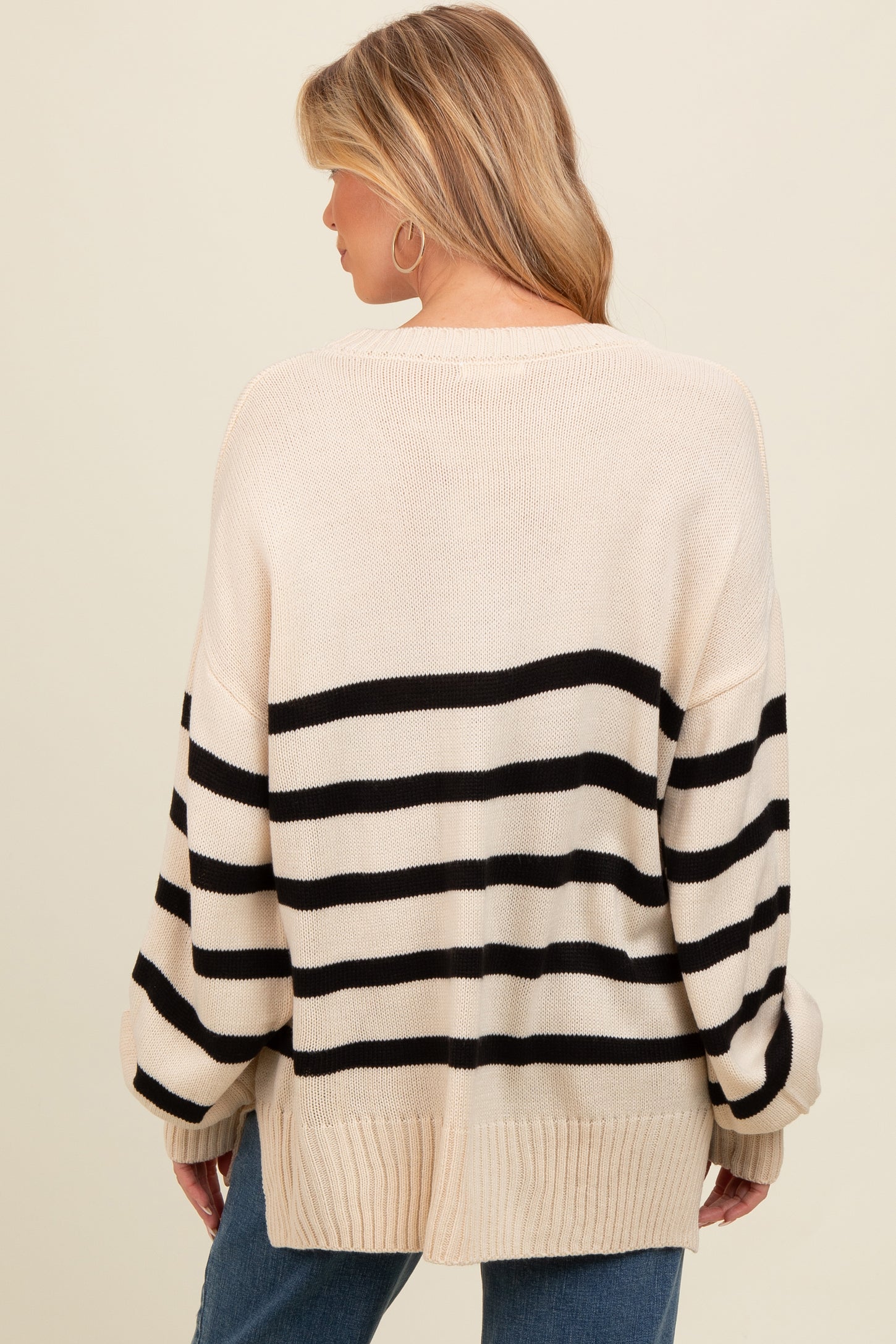 woman wearing a cream and black striped oversized maternity sweater, seen from the back