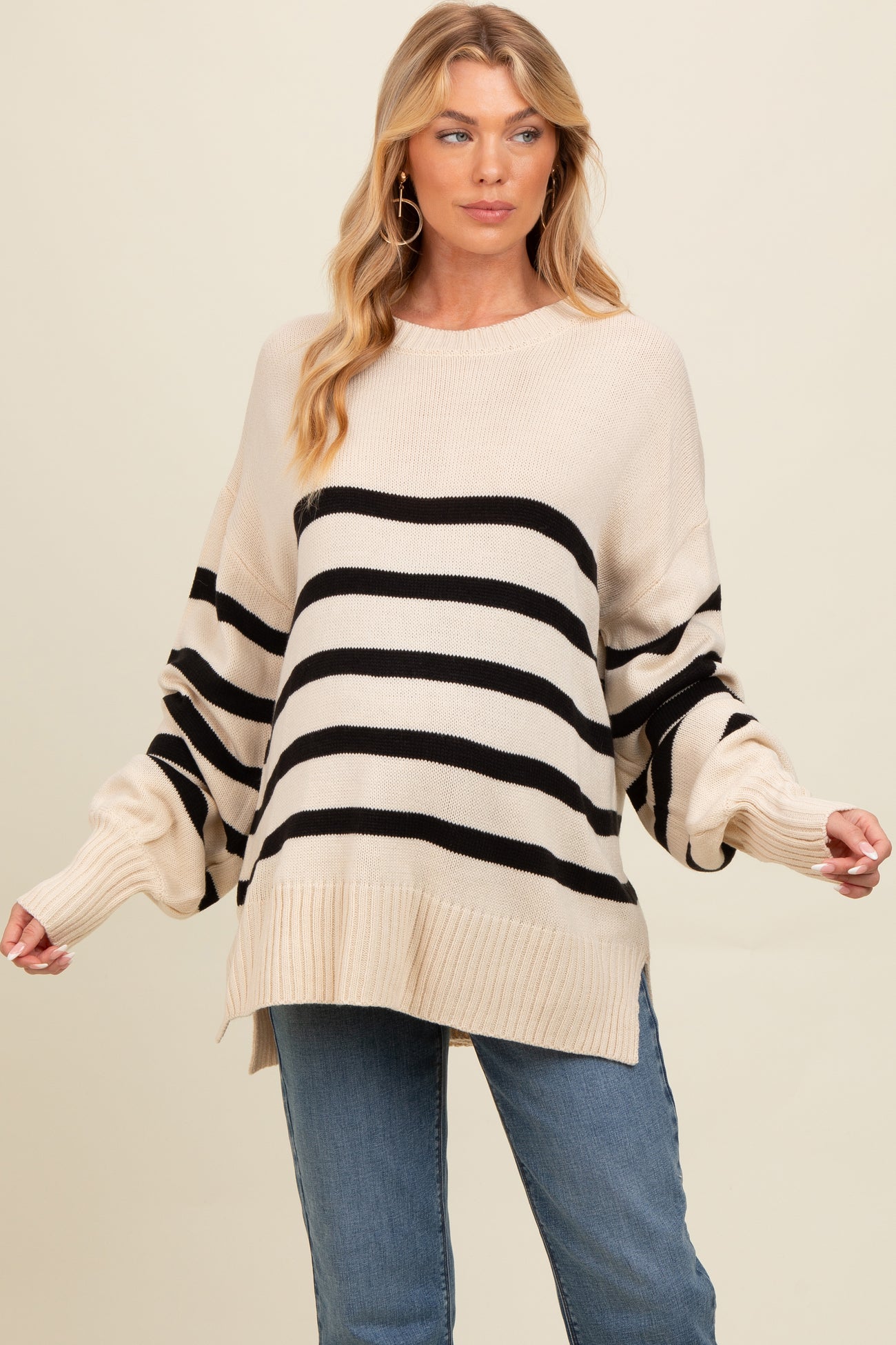 woman wearing a beige and black striped oversized maternity sweater with wide sleeves and relaxed fit