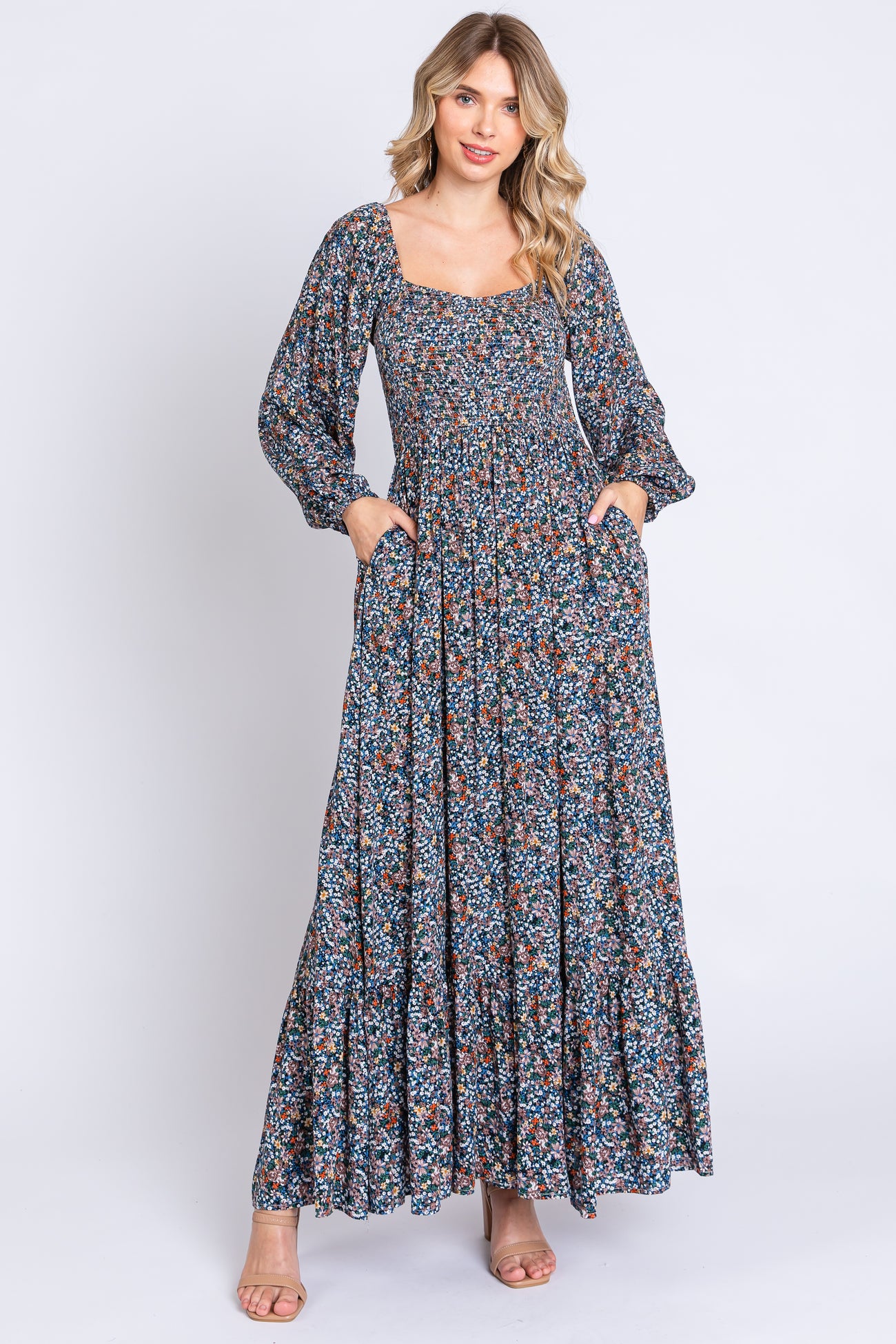 woman wearing a long floral maxi dress with puff sleeves and a square neckline, featuring side pockets