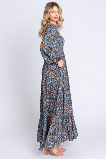 woman wearing a long floral maxi dress with long sleeves and pockets, standing in profile