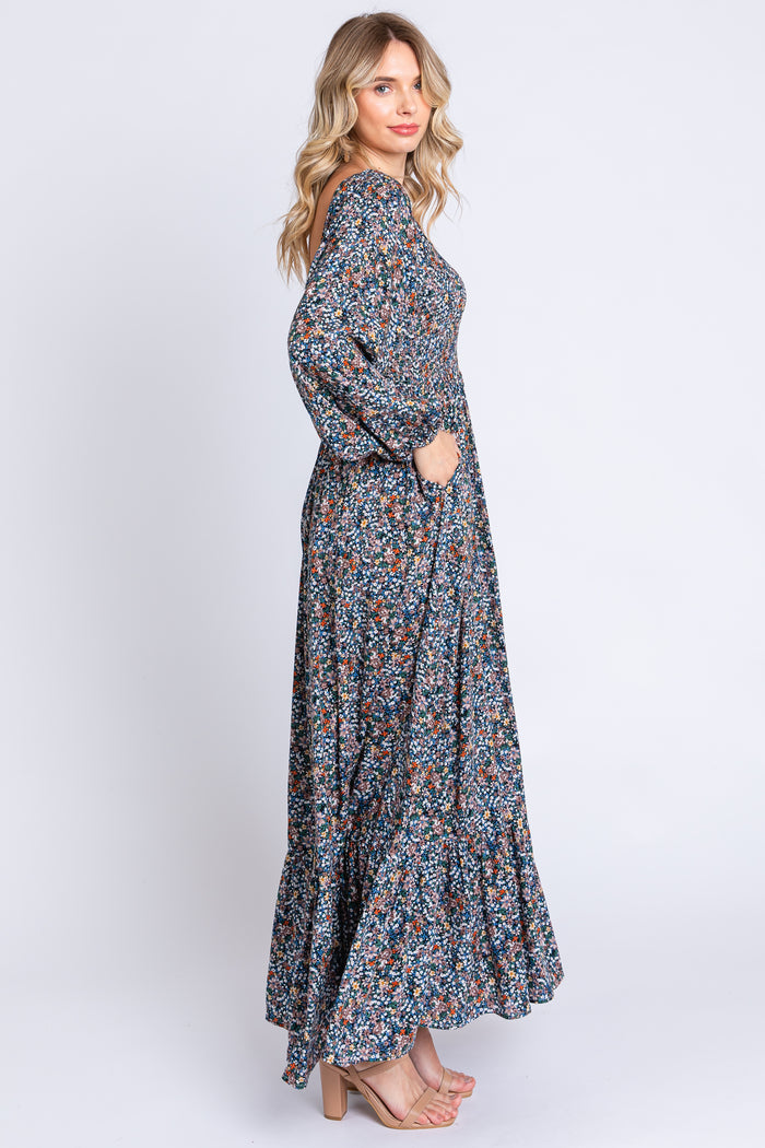 woman wearing a long floral maxi dress with long sleeves and pockets, standing in profile