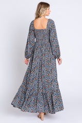 woman wearing a long floral maxi dress with a square neckline and long puff sleeves, showing the back view