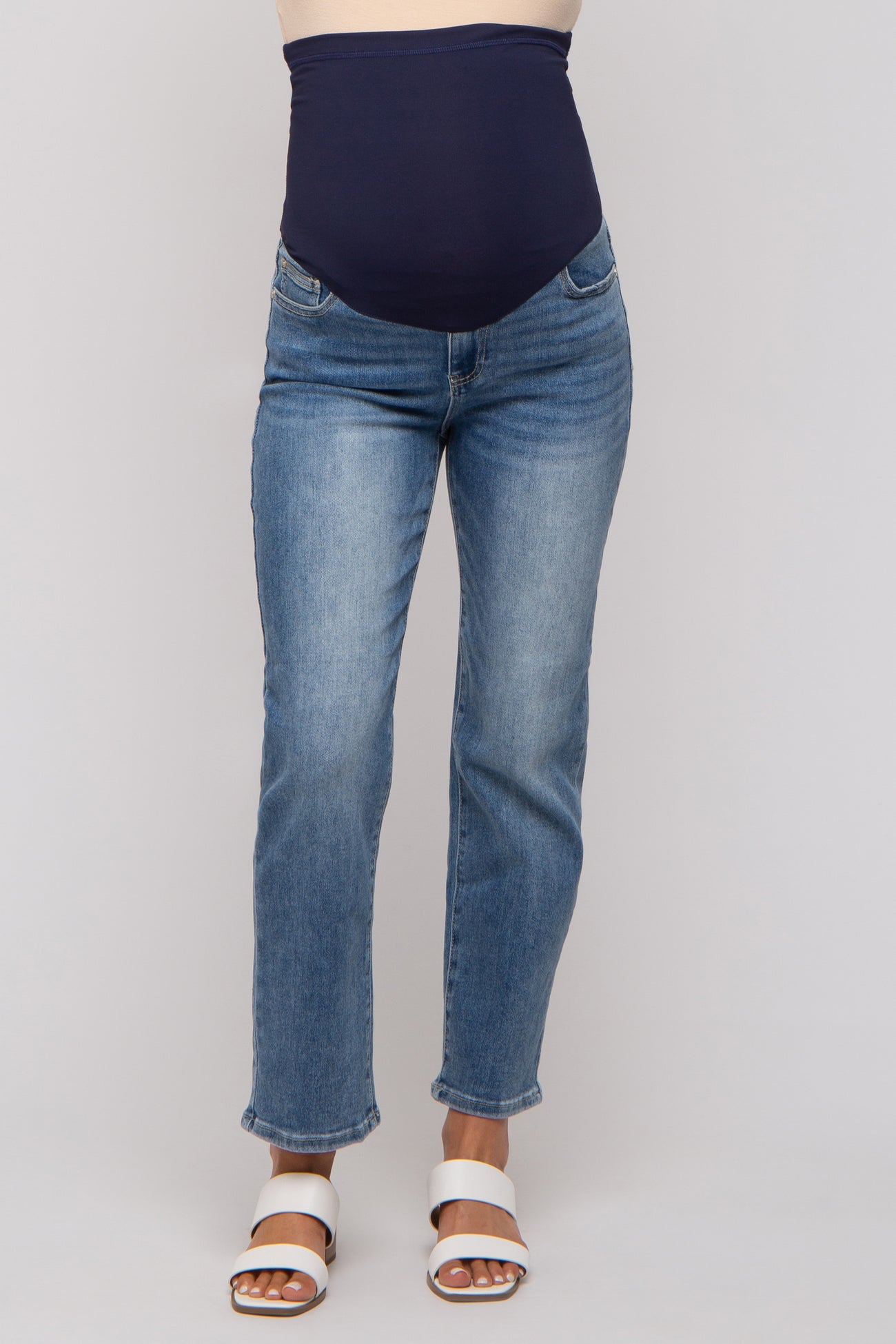woman wearing a maternity pair of blue straight leg jeans with a navy blue over-the-bump waistband