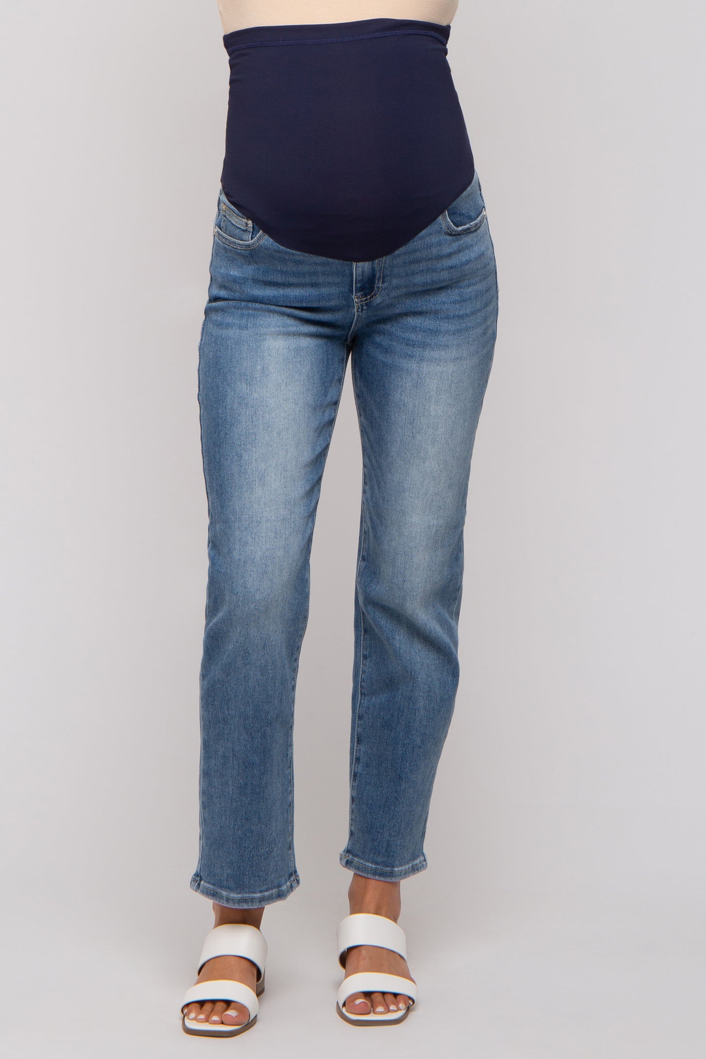 woman wearing a maternity pair of blue straight leg jeans with a navy blue over-the-bump waistband