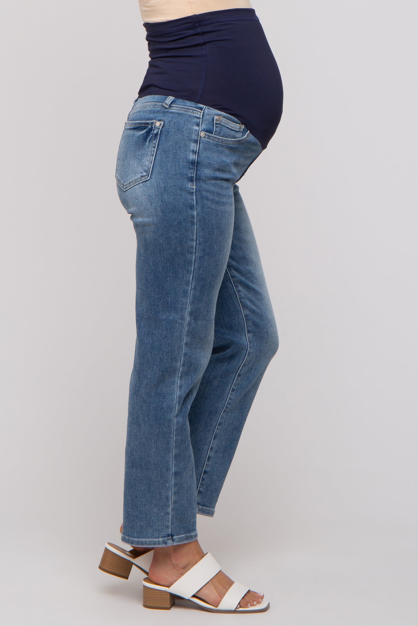 woman wearing maternity blue jeans with a dark blue belly band, showing a visible baby bump