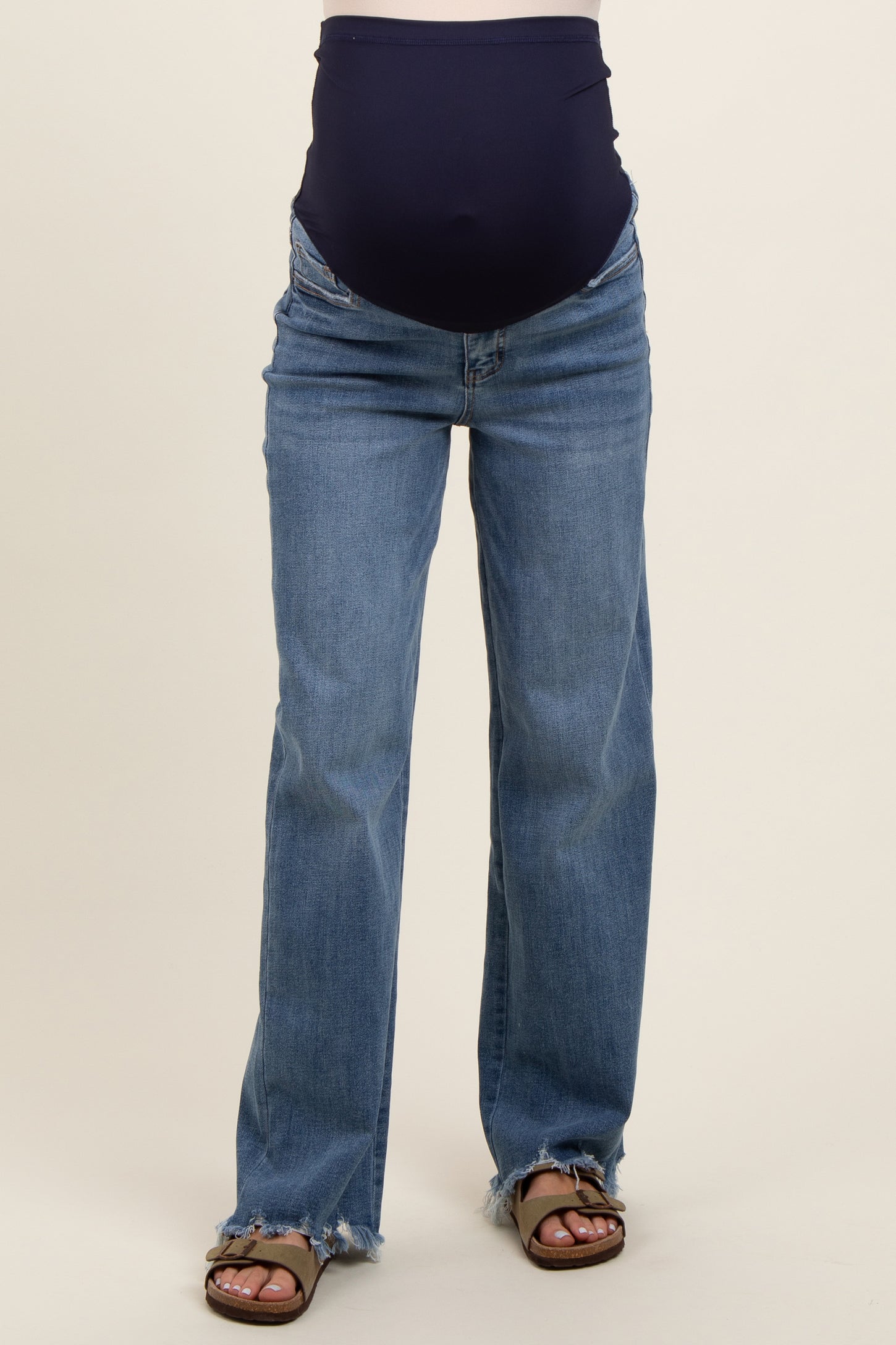 woman wearing a pair of distressed blue maternity jeans with a navy over-the-bump panel.
