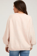 woman wearing a soft pink oversized maternity sweater with balloon sleeves, viewed from the back