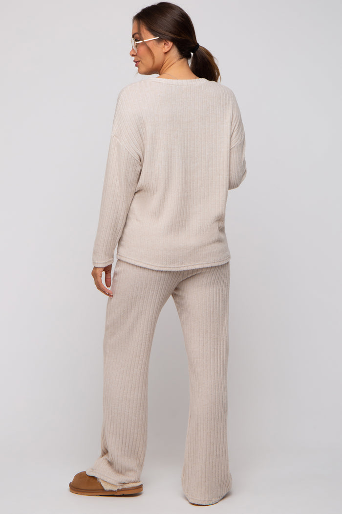 woman wearing a beige ribbed maternity loungewear set with long sleeves and wide-leg pants, showing a relaxed fit from behind