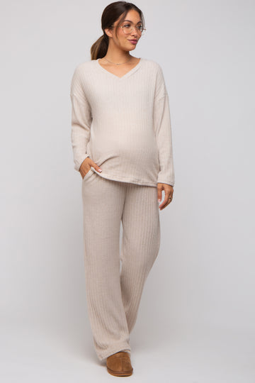 woman wearing a beige ribbed maternity top and matching pants, showcasing her baby bump, styled with glasses and a relaxed fit