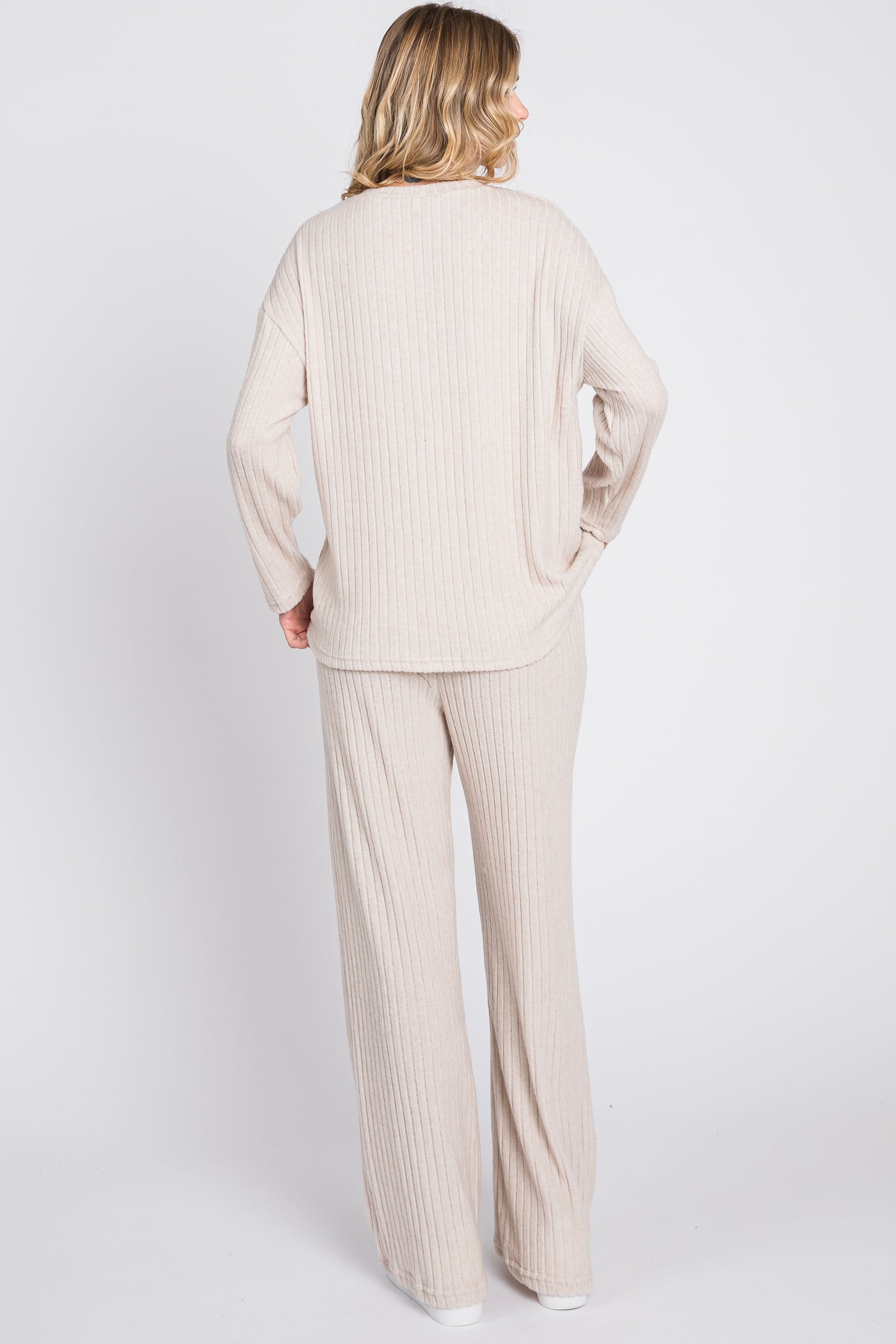 woman wearing a beige ribbed knit long sleeve top and matching wide-leg pants, view from the back