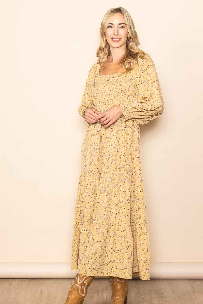 woman wearing a yellow floral maxi dress with long puff sleeves and a square neckline