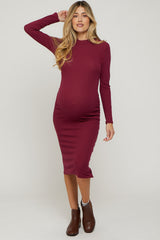 woman wearing a burgundy long sleeve maternity dress highlighting her baby bump