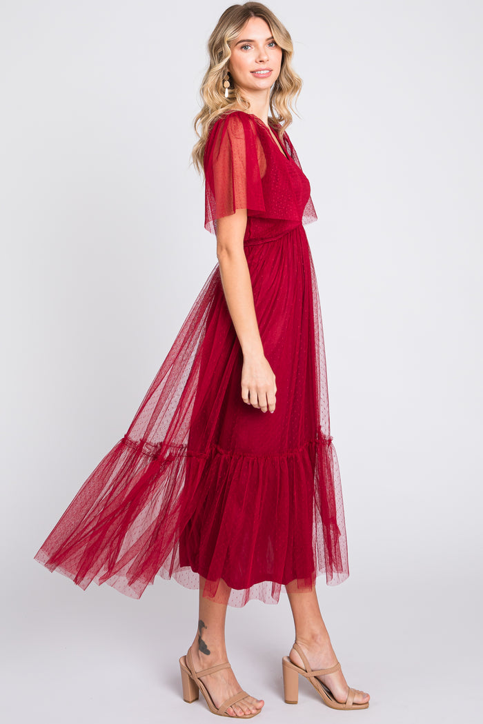 woman wearing a burgundy tulle maxi dress with short sleeves and a ruffled hem, styled with nude heels