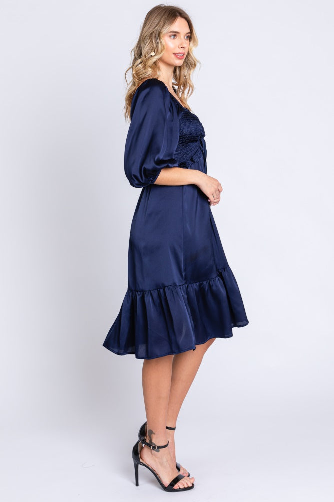 woman wearing a navy blue off-the-shoulder smocked dress with a ruffled hem and puff sleeves