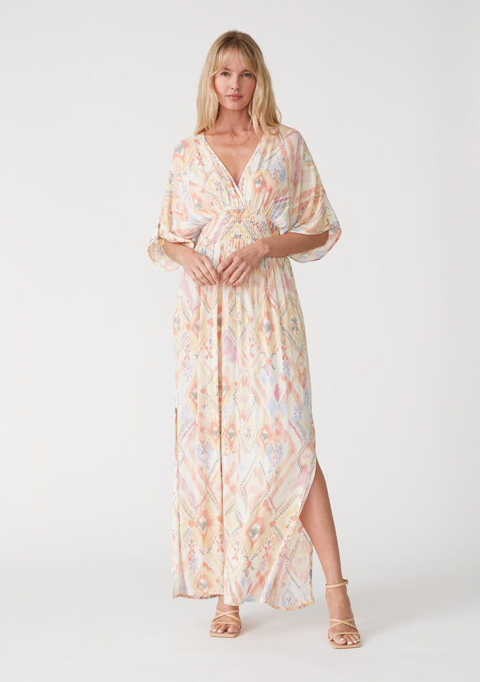 woman wearing a colorful patterned maxi dress with a v-neckline and slits on the sides
