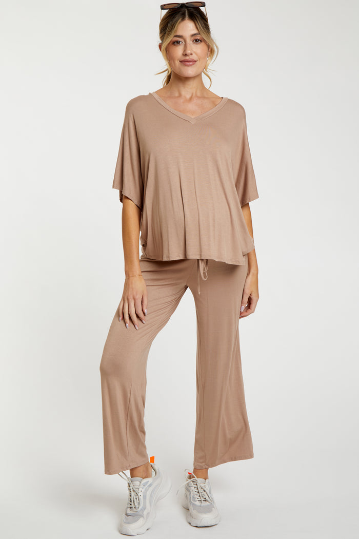 woman wearing a light brown maternity loungewear set with a flowy top and loose pants