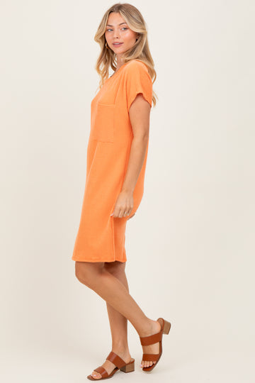 woman wearing an orange short sleeve ribbed dress with a pocket and styled with brown sandals