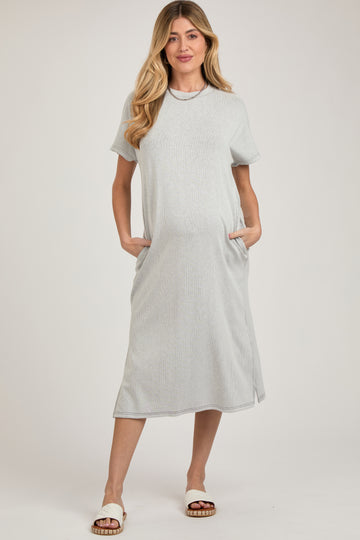 woman wearing a light gray striped maternity dress with short sleeves and pockets, showing her baby bump