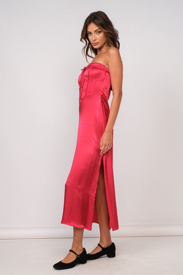 woman wearing a hot pink strapless satin dress with a side slit and tied detail at the bust