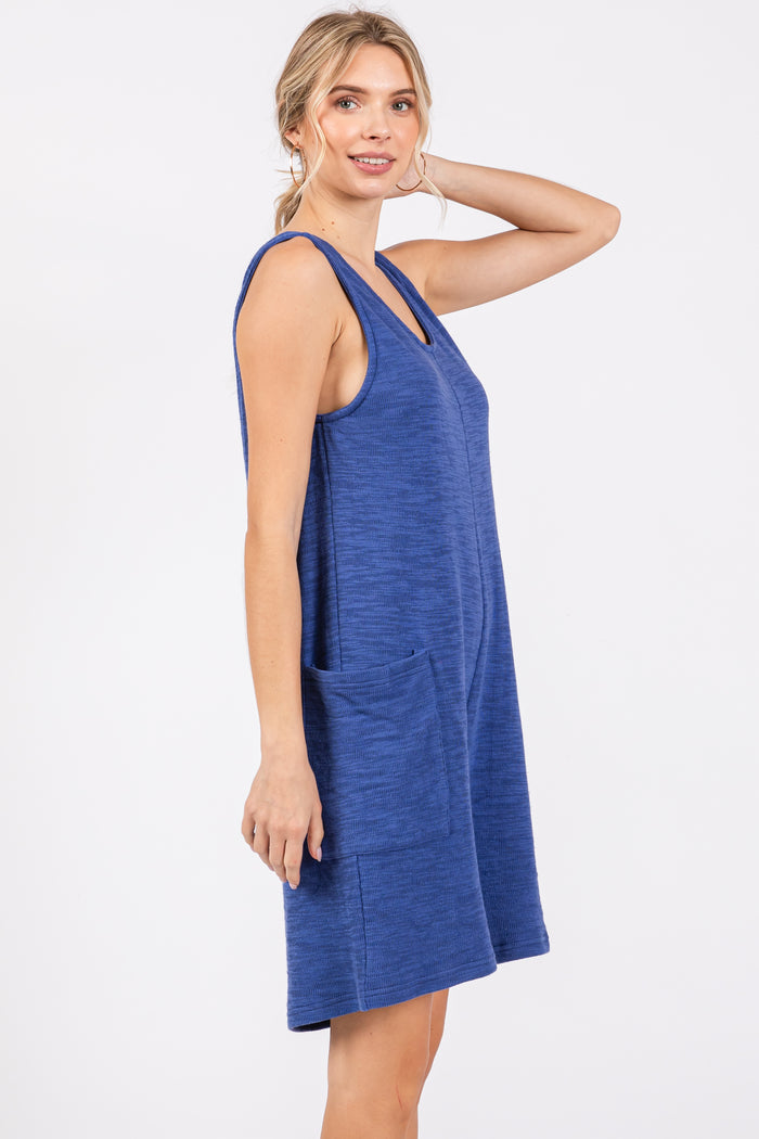 woman wearing a dark blue sleeveless shift dress with side pockets