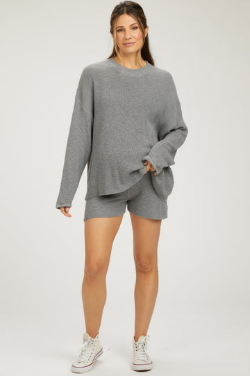 woman wearing a gray knitted maternity lounge set with oversized sweater and matching shorts, baby bump visible