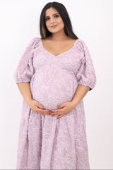 woman wearing a lavender floral maternity dress with puff sleeves and holding her baby bump