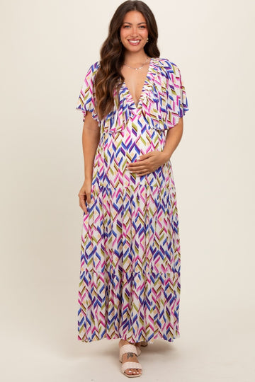 woman wearing a colorful patterned maternity maxi dress and holding her baby bump