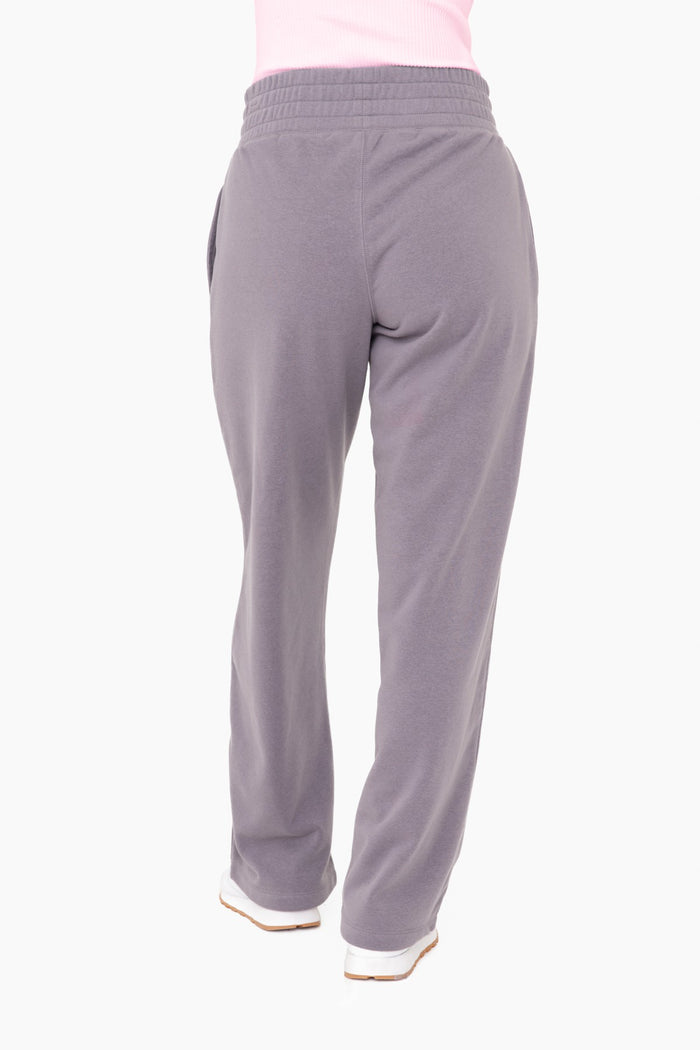 woman wearing gray sweatpants with an elastic waistband and side pockets, shown from the back