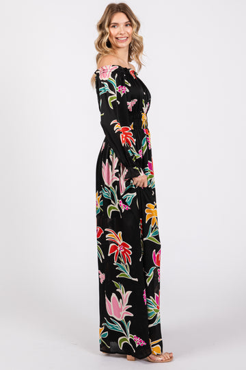 woman wearing a black off-the-shoulder maxi dress with colorful floral prints and long sleeves