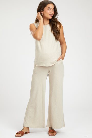woman wearing a light beige maternity set with sleeveless top and wide-leg pants, featuring a visible baby bump