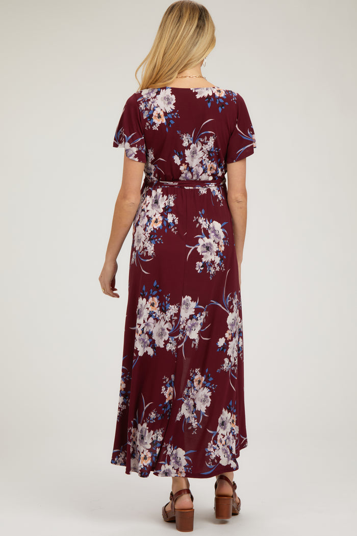 woman wearing a maroon floral maternity maxi dress with short sleeves and a tie waist from the back