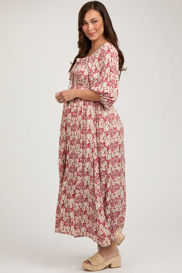 woman wearing a pink floral maternity maxi dress with a gathered waist and three-quarter sleeves, showcasing her baby bump