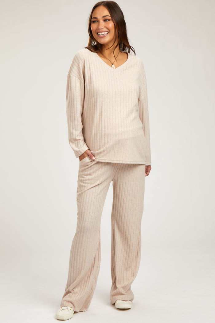 woman wearing a beige maternity loungewear set with long sleeve top and matching pants, smiling and highlighting her baby bump