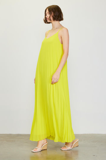 woman wearing a bright yellow pleated maxi dress with spaghetti straps and strappy sandals