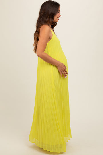 woman wearing a bright yellow pleated maternity maxi dress and showcasing her baby bump