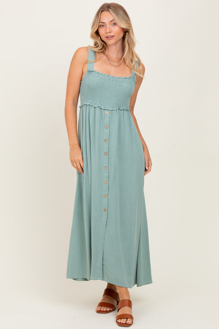 woman wearing a sage green smocked bodice maxi dress with buttons and straps