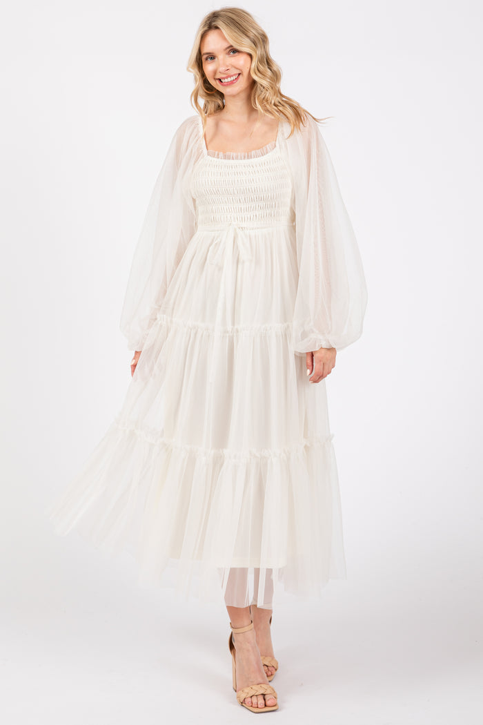 woman wearing a white tiered maxi dress with sheer puff sleeves and a smocked bodice