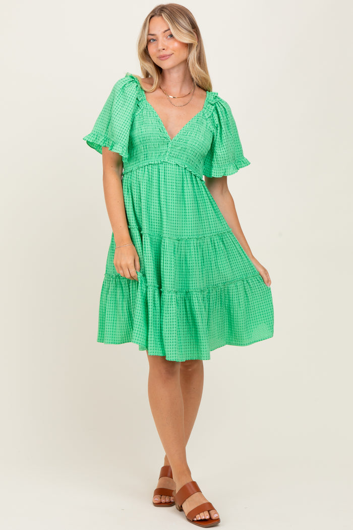 woman wearing a green gingham tiered dress with puff sleeves and a v-neckline