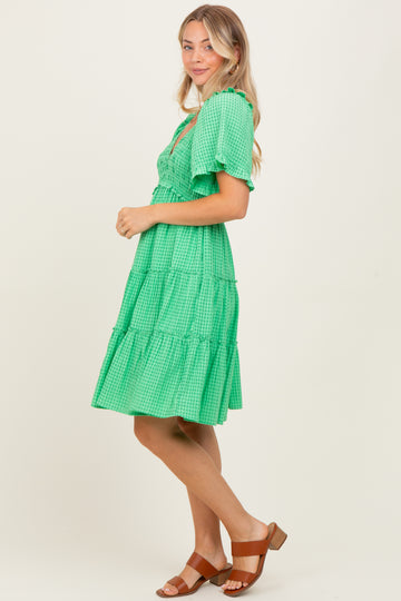 woman wearing a green tiered midi dress with short sleeves and a ruffled neckline