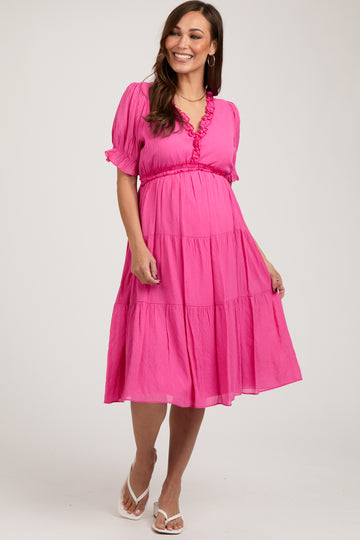 woman wearing a pink tiered maternity dress with ruffled neckline and short sleeves, showing her baby bump