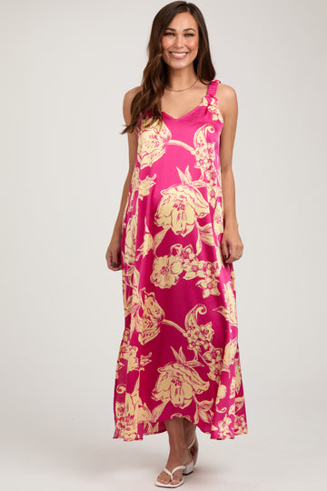 woman wearing a pink floral maternity maxi dress with adjustable straps and a flowing silhouette, showing her baby bump
