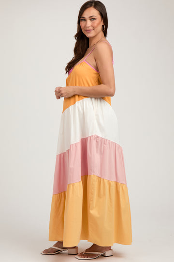 woman wearing a colorful maternity maxi dress with yellow, white, and pink tiers, showcasing her baby bump