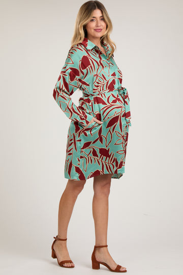 woman wearing a mint green maternity dress with a leaf print and a tie belt, showcasing her baby bump