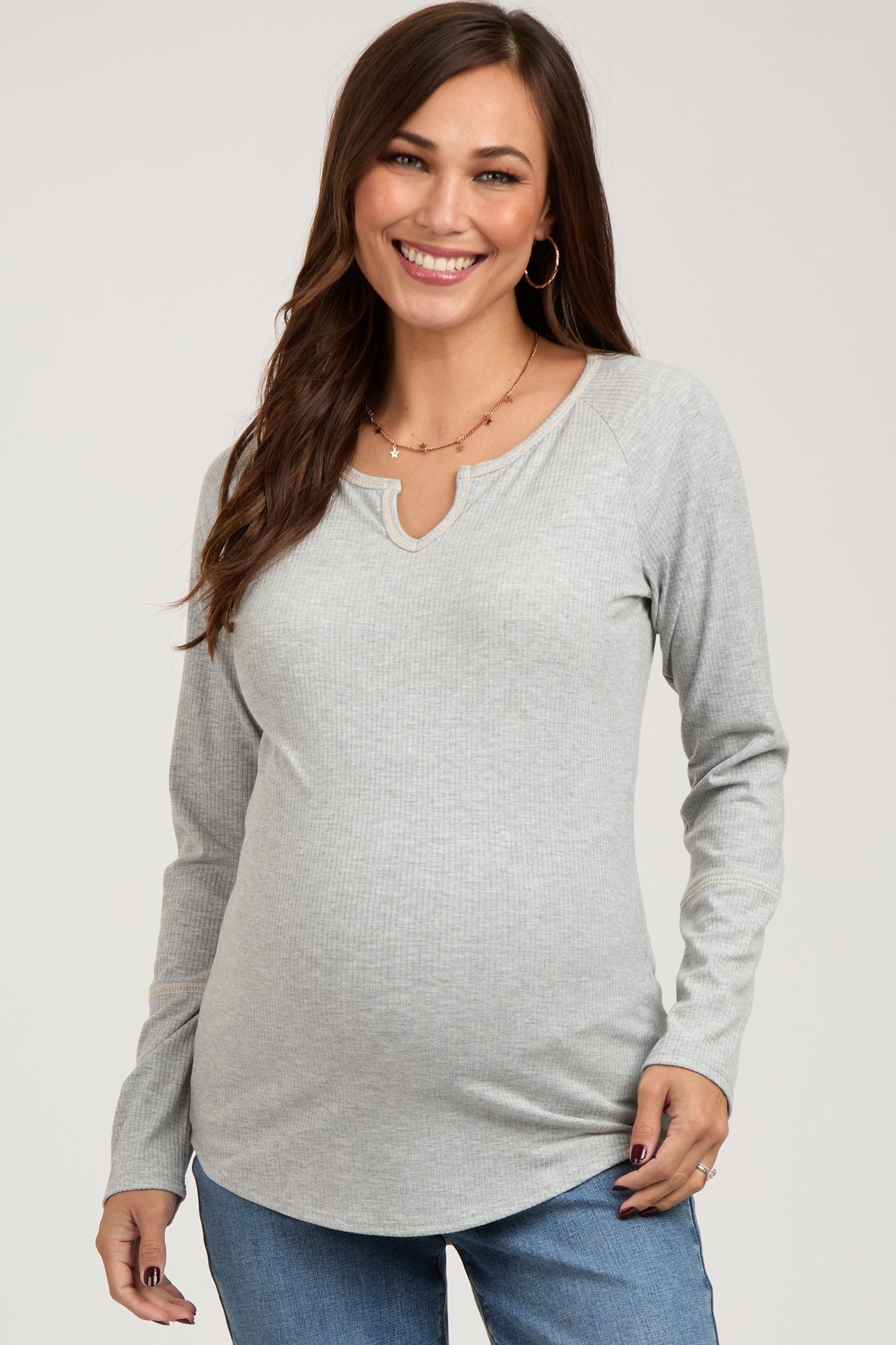 woman wearing a light gray long sleeve maternity top with a keyhole neckline and a visible baby bump