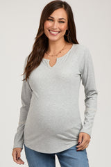 woman wearing a light gray long sleeve maternity top with a keyhole neckline and a visible baby bump