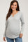 woman wearing a light gray long sleeve maternity top with a keyhole neckline and a visible baby bump