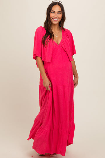 woman wearing a bright pink maternity maxi dress with a matching lightweight cardigan and a visible baby bump
